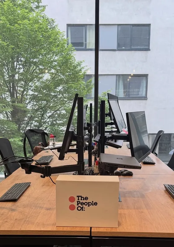 The new office after the move: clear desks with monitors on arms and keyboards set out, in front of a big window